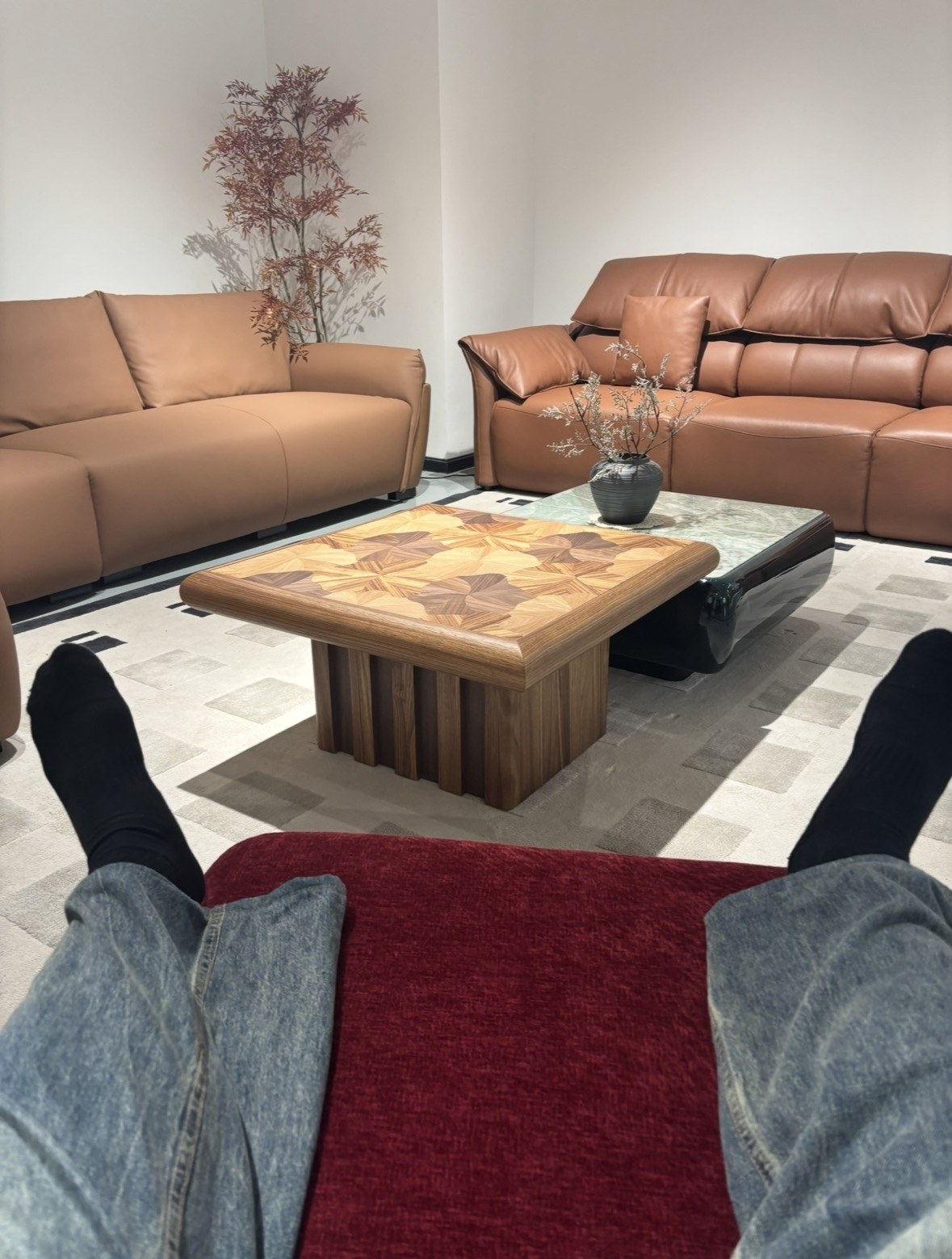A seat-level view of leather sofas and a marquetry coffee table in a furniture showroom