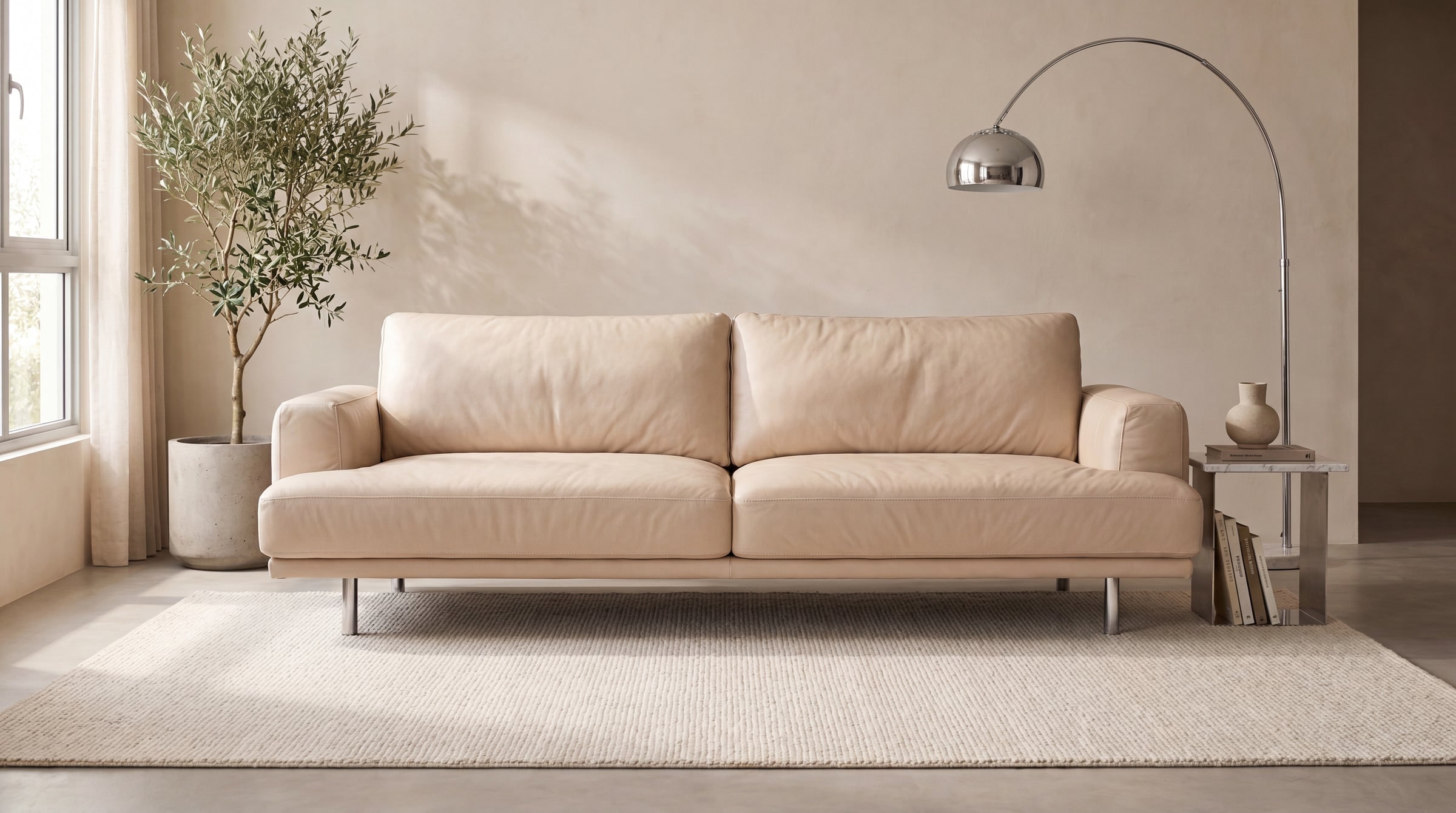 A cream leather Nomor sofa in a bright living room with an arc floor lamp