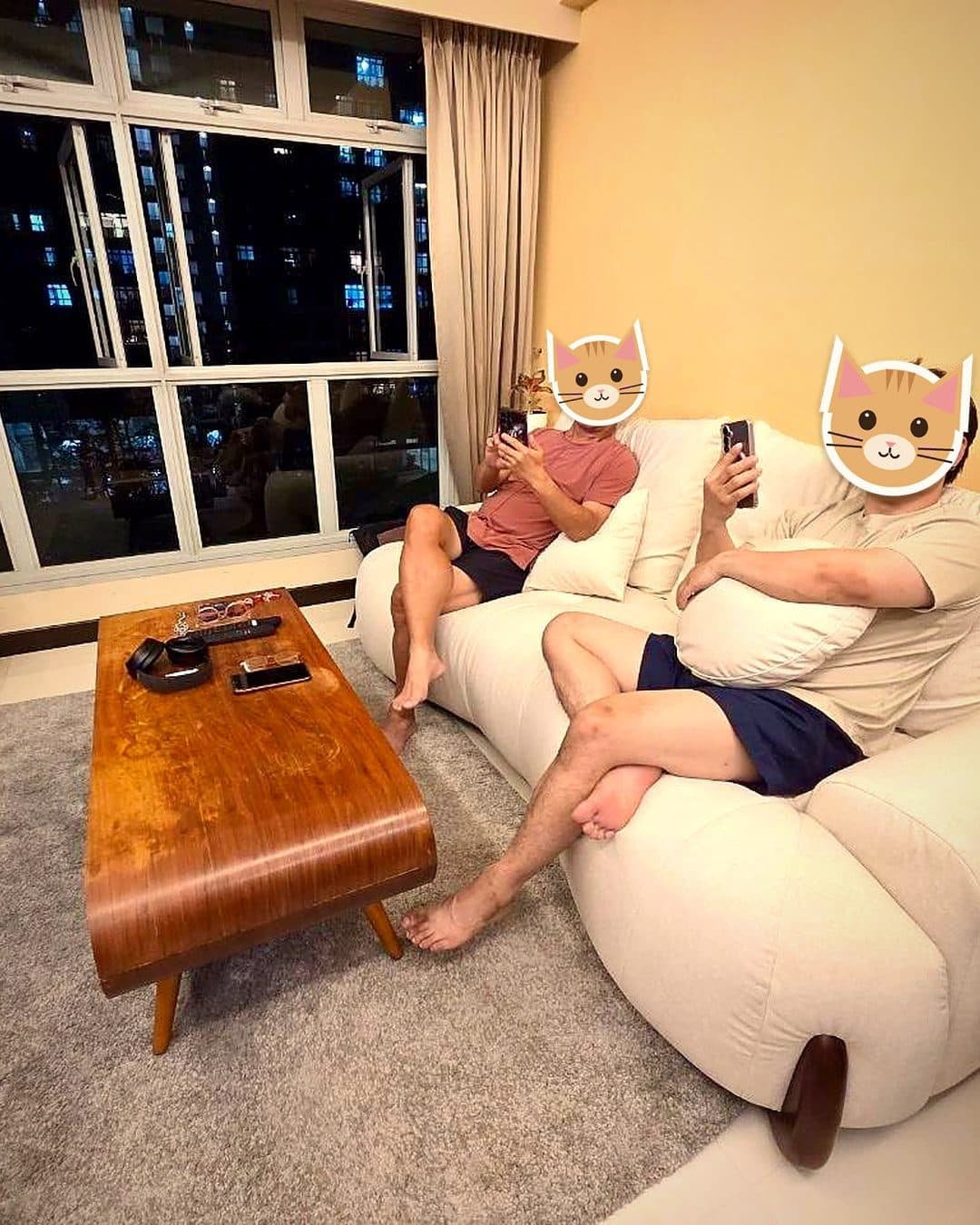 Two people on a cream sofa beside a timber coffee table, with a clear walkway, in an HDB living room at night