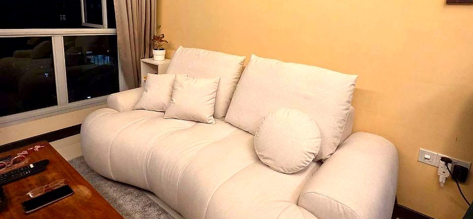 A cream sofa with round cushions in a warm-toned HDB living room