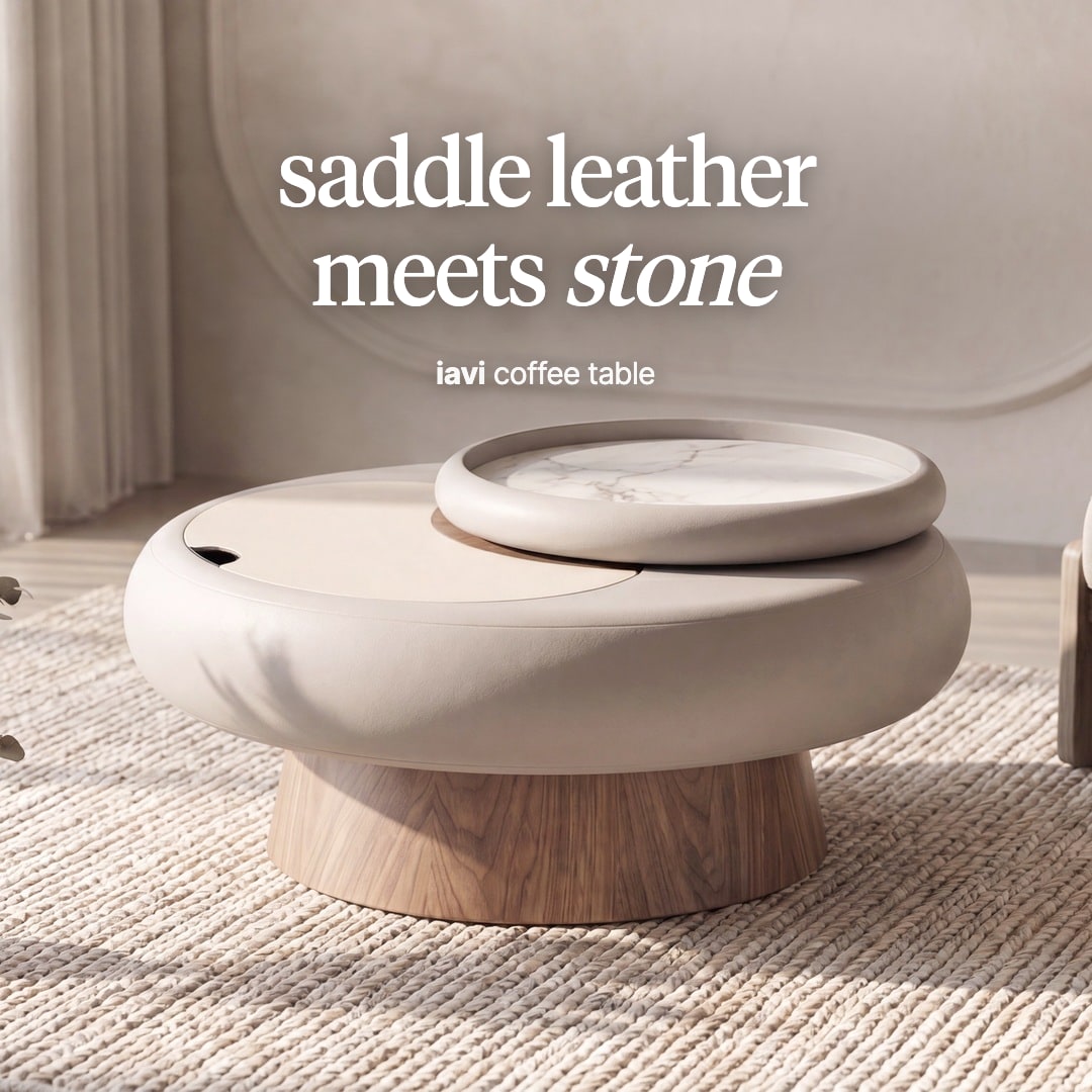 Iavi round coffee table with an ivory leather-wrapped top, a small stone tray and a wooden pedestal. The image reads "saddle leather meets stone, iavi coffee table".