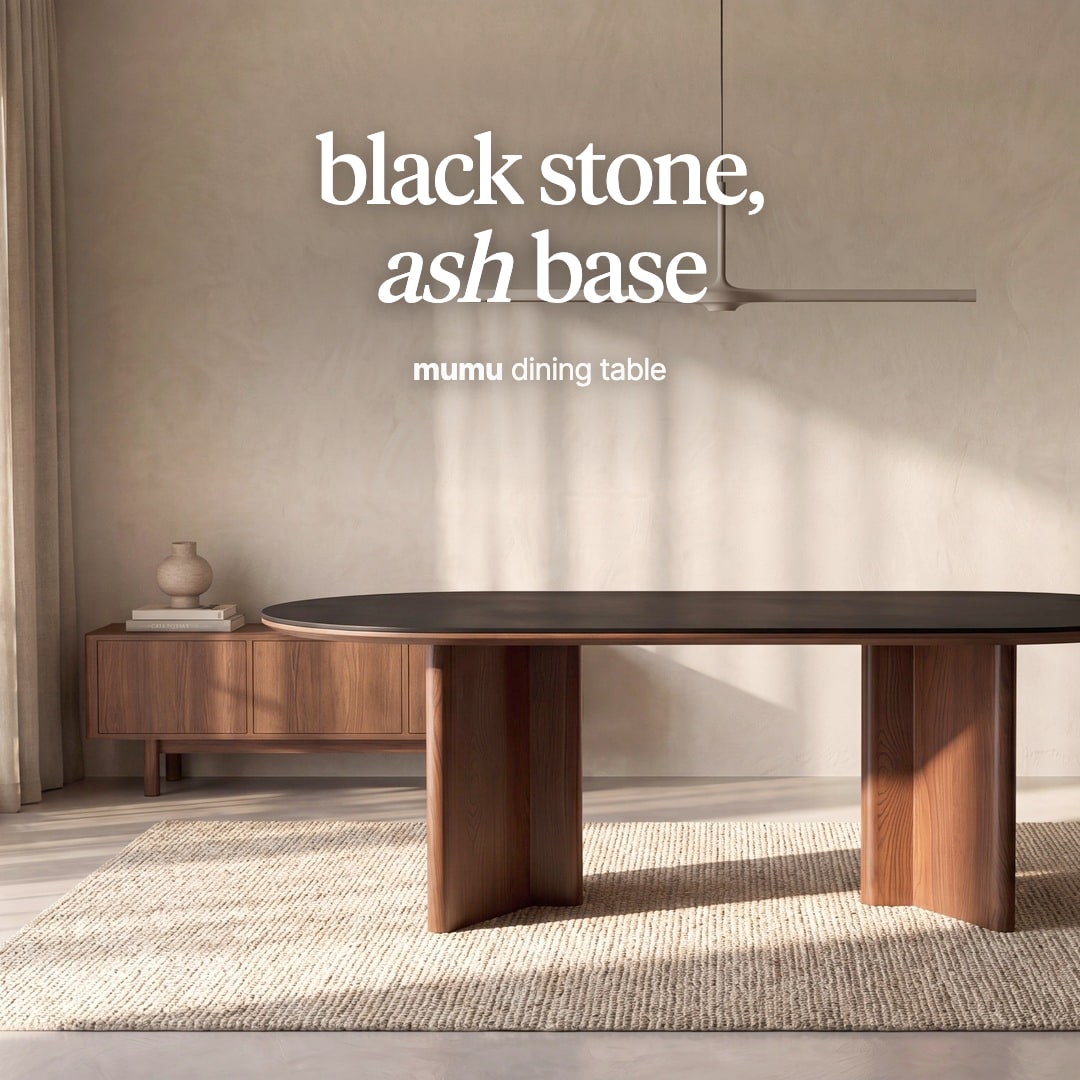 Mumu oval dining table with a black stone top on two wooden pedestals. The image reads "black stone, ash base, mumu dining table".