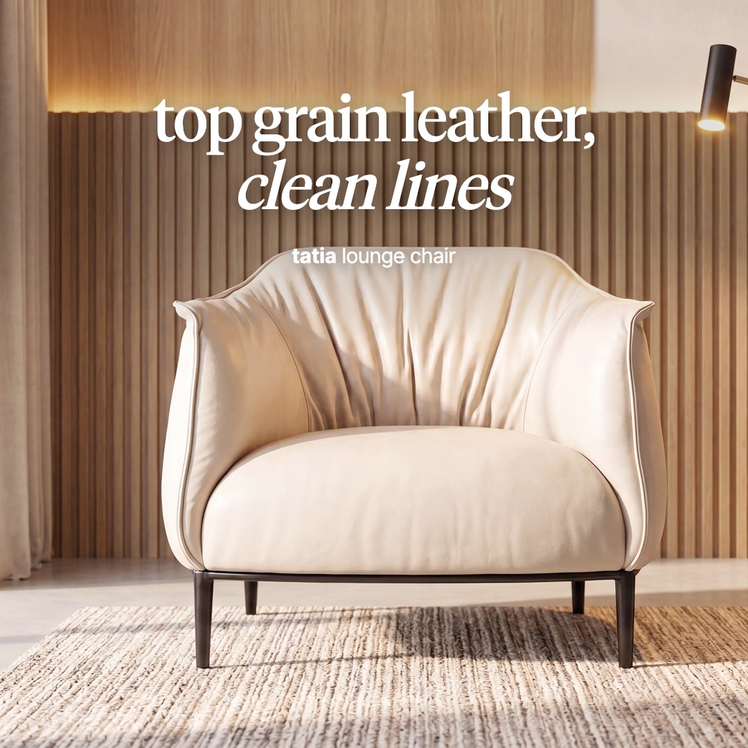 Tatia lounge chair in cream leather with a gathered back on slim dark legs. The image reads "top grain leather, clean lines, tatia lounge chair".