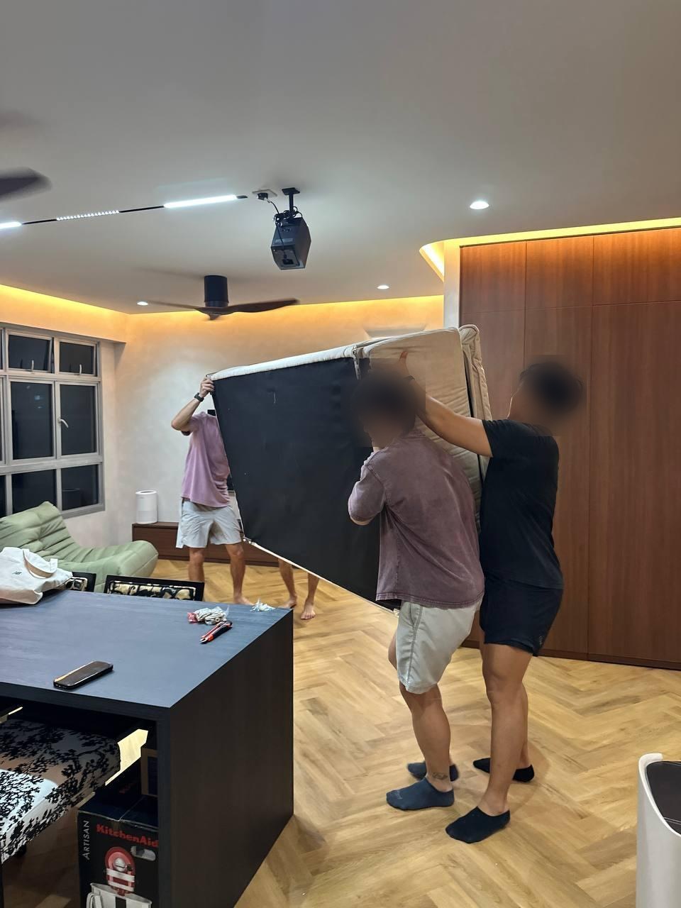 Two people carrying a sofa into place in a 4-room BTO living room