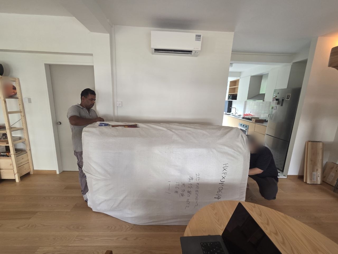A mover unwrapping a plastic-wrapped sofa in a living room