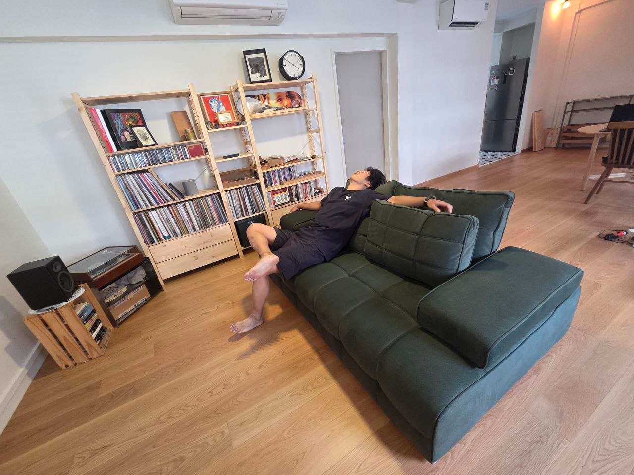 Ray lounging happily on his forest-green modular sofa in his Tiong Bahru flat