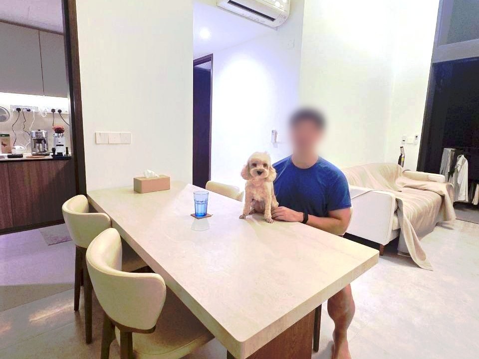 Javier sitting at his travertine Mesi dining table with his poodle Mochi in a Tampines flat